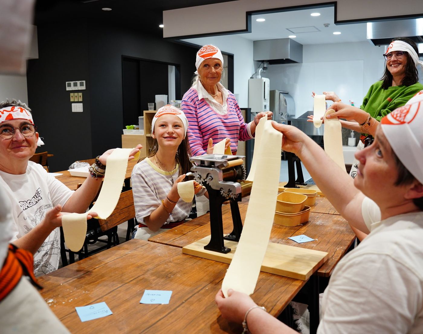 Guests stretching fresh ramen dough at a long table