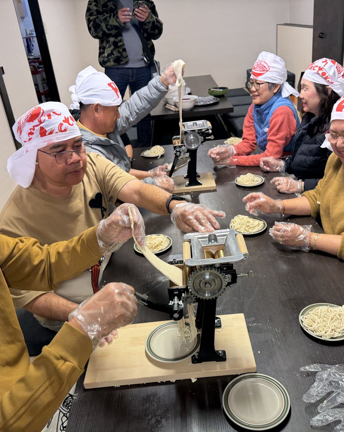 Group of guests making noodles with a noodle machine